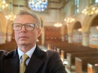 a man in glasses is taking a selfie in a church